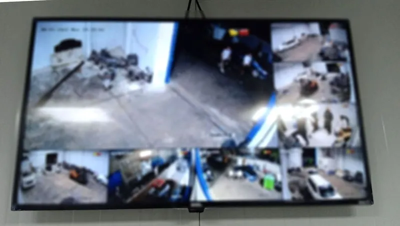 CCTV monitor in a vehicle workshop office showing multiple camera views (screen blurred for privacy)
