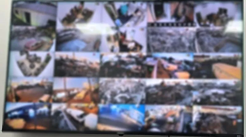 Wall-mounted screen showing a 20-camera CCTV grid for an industrial yard (screen blurred for privacy)