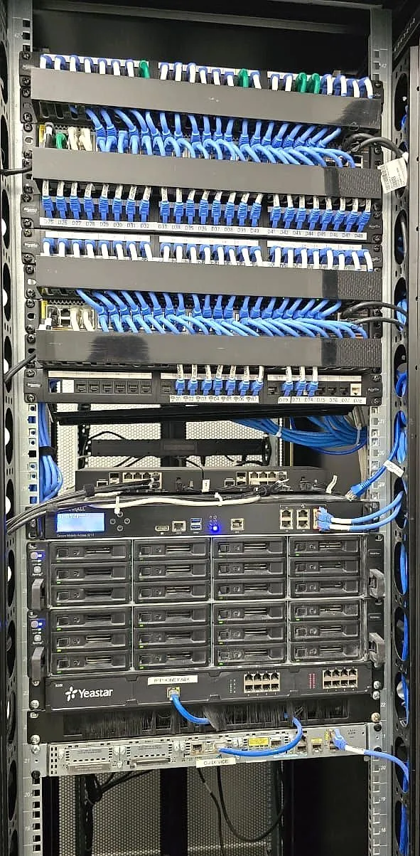 Network rack with labelled patch panels, switches, storage and a Yeastar IP PBX
