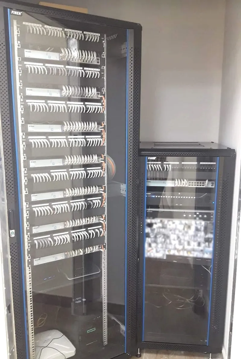 Two floor-standing network racks with patch panels and switches in an office comms room